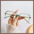 Eleganti occhiali grandi anti-luce blu con montatura sfumata verde tenuti in mano. - Stile Verde Traslucido (TR30087)
