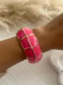 Close-up detail of a vibrant rose pink enamel bangle bracelet worn on a female wrist - Grid Texture Style / Fuchsia 3556