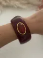 Primo piano di un bracciale in resina bordeaux con finta pietra rossa montata su polso - Rosso Vino (1582)