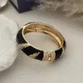 Detailopname van vintage zwarte emaille armband met gouden veren patronen - Zwart Goud Veer Stijl / Goud