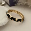Gedetailleerde weergave van een vintage zwart emaille en goudkleurige luxe armband - Zwart En Goud Tweekleurige Stijl / Goud