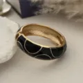 Detailweergave van een vintage gouden armband met zwart emaille en golfdesign - Zwart Goud Polkadots Stijl (3557) / Goud