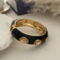 Primo piano di un bracciale rigido vintage in smalto nero con cristalli ambrati - Stile Intarsiato con Strass Nero e Oro (2557) / Oro
