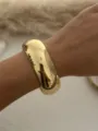 Nahaufnahme eines breit polierten Goldarmreifens an einem Handgelenk einer Frau - Gold (555)