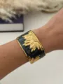Eleganter gold-schwarzer offener Armreif aus Edelstahl mit geprägtem Sonnenblumenmuster - Schwarz Gold Muster