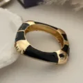 Primo piano di un bracciale rigido vintage in smalto nero e oro a onde - Stile Onde Nero e Oro (2583) / Oro
