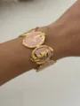 Eleganter vergoldeter Armreif mit rosa Emaille-Einsätzen und detailliertem Seestern-Motiv - Rotgold Blumenwellenstil