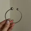 Primo piano di un bracciale rigido argento minimalista con doppie estremità a sfera. - Stile Aperto a Doppia Sfera (1812417) / Argento
