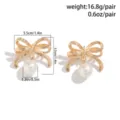 Eleganti orecchini a fiocco dorati con perle bianche pendenti e accenti di cristallo - Orecchini a Bottone (653108) / Oro