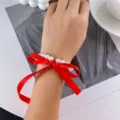 Close-up of elegant white pearl bracelet with a large red ribbon bow on a wrist - Bracelet Style (872211) / Red