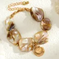 Nahaufnahme von unregelmäßigen Perlmuttmuschelstücken mit einem goldenen Muschel-Anhänger - Armband (1052488) / Weiß