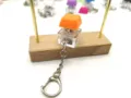 Detailed view of an orange mechanical switch keycap keychain on a wooden display stand - Orange