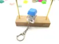 Blue mechanical keyboard switch keychain fidget toy on a wooden display stand. - Blue