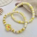 Detaillierte Makroansicht von gelb-weißen Heishi-Perlenarmbändern mit gelber Blumenverzierung - Gelb und Weiß Blume Polymer-Ton Armband (5933) / 2er Set