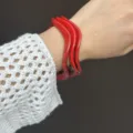 Dettaglio di bracciali geometrici rossi in resina indossati con manica all'uncinetto. - Stile a Onda Semplice (03022) / Set di 3 pezzi / rosso Angola