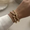 Detailaufnahme des stylischen, vergoldeten, geschwungenen Federknoten-Armreifs - Knoten Design Kreuz Armreif (217) / Gold