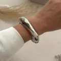 Nahaufnahme eines massiven, polierten, silberfarbenen Wassertropfen-Armreifs am Handgelenk - Ovales Glattes Stil (213) / Silber
