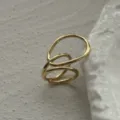 Detaillierte Nahaufnahme eines minimalistischen goldfarbenen unregelmäßigen hohlen Rings - Offener Wickelstil (Kupfer 213) / Gold