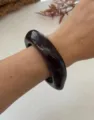 Vista dettagliata di un bracciale rigido geometrico marmorizzato rosso Angola su polso - Stile Geometrico Minimalista / Marmo Nero