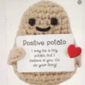 Handmade crochet positive potato plush toy close-up detail showing cute face and card. - Smiling Potato without Red Heart