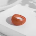 Makroaufnahme eines durchscheinenden orangefarbenen Harzrings mit dezentem Goldglitzer - Bernstein Orange Goldpulver Geometrisch (R179_6)