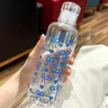 Close-up of handheld transparent plastic water bottle with blue bow and heart patterns - 500ml / Blue Bow