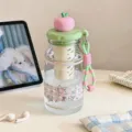 Portable aesthetic water bottle with tea infuser and cute fruit-shaped lid on a desk. - 8015 Pink Green Fruit Lid