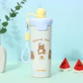 Detailansicht einer gelben isolierten Edelstahlflasche mit Bärenmotiv und blauem Band - 600ml / Gelb