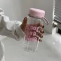 Gros plan d'une bouteille d'eau en plastique avec bouchon rose et graduations - Rose Fille 550ml