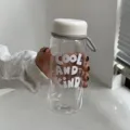 Vue détaillée d'une bouteille d'eau en plastique avec le texte 'Cool and Kind' - Blanc Crème 550ml