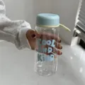 Détail d'une bouteille d'eau en plastique transparent avec bouchon bleu et texte COOL AND KIND - Bleu Ciel 550ml