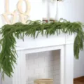 Artificial Norfolk Pine garland draped over a white fireplace for Christmas decor. - 120cm