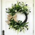Beautiful artificial olive wreath with a burlap bow and flowers on a white door - Olive Half-Sided Wreath