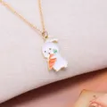 Detail of a cute cartoon rabbit pendant with a carrot on a delicate gold necklace chain - White Rabbit Holding Carrot Style