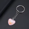 Close-up detail van een hartvormige sleutelhanger met LOVE-print en handafbeelding. - Handen Hart LOVE Stijl (YSL-3)