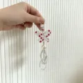 Detailed close-up of a butterfly charm with elegant pearls and white bead tassels - Rose Red