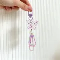 Close-up detail of a colorful beaded butterfly keychain accessory with a large pearl charm. - Purple