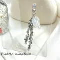 Detail of iridescent angel wing and star chain tassel on a silver metal keychain - White