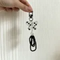 Detailed view of a handmade butterfly phone charm with a white pearl and black bead loops - Black