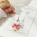 Close-up of a cute bitten apple phone charm with a red gingham bow and stars. - Bowknot Strap Style