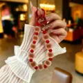 Colorful beaded phone strap with matte brown and red charms shown being held by hand - Creative Colorful Jelly Beads (yc5360) / Brown