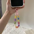 Close-up of a hand holding a colorful irregular stone beaded phone strap on a white case - Random Mixed Style (yc5342) / Pastel Colors