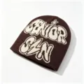 Close-up of brown knitted beanie featuring cream SENIOR SIN jacquard and star detail - Letter Jacquard Style / Coffee