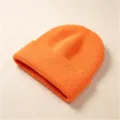 Nahaufnahme einer leuchtend orangefarbenen Rippstrickmütze für den Winter. - Rippenstrick-Umschlagmütze / Orange