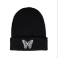Macro view showing the detailed white butterfly embroidery on a black knitted beanie - One Size / Butterfly Embroidery Style / Black