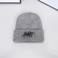 Detailed close-up of a grey knitted winter beanie hat with bold black 'HEART' embroidery. - One Size / Embroidered Letter Beanie / Gray