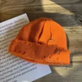 Detailopname van een oranje gebreide muts met ringen en een veiligheidsspeld detail - Oranje