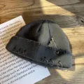 Gedetailleerd zicht op grijze beanie met veiligheidsspeld en metalen ringen - donkergrijs