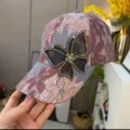 Close-up of a sparkling rhinestone butterfly on a women's pink lace baseball cap - Bowknot Style / Burgundy