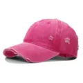 Nahaufnahme einer rosa gewaschenen Baumwoll-Basecap im Distressed-Look mit Löchern. - Einheitsgröße(Einstellbar) / Fuchsia